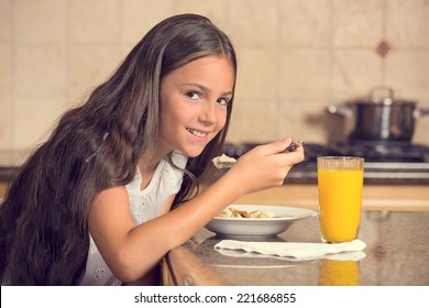 Cute Teenager Girl Eating Cereal With Milk Drinking Orange Juice For Breakfast In The Kitchen