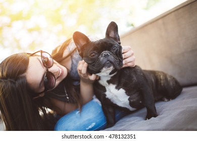Cute teenager girl enjoying outdoors in cafe bar together with her adorable French bulldog puppy. Strong back light. Warm sunny day. - Shutterstock ID 478132351