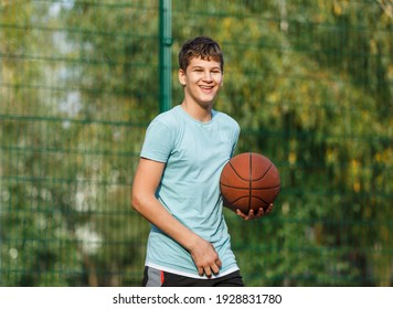 Cute Teenager in green t-shirt with orange basketball ball plays basketball on street playground in summer. Hobby, active lifestyle, sports activity for kids.	 - Powered by Shutterstock