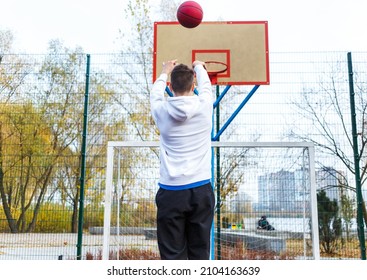 Cute teenager in white hoodie playing basketball. Young boy with red ball learning dribble and shooting on the city court. Hobby for kids, active lifestyle - Powered by Shutterstock