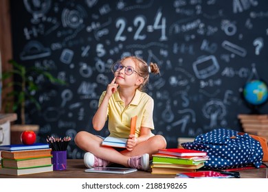 Cute thoughtful tired schoolgirl with glasses. Sitting at his desk at home and bored. Back to school. Little girl C does not want to get knowledge and do homework. Learning problems - Powered by Shutterstock