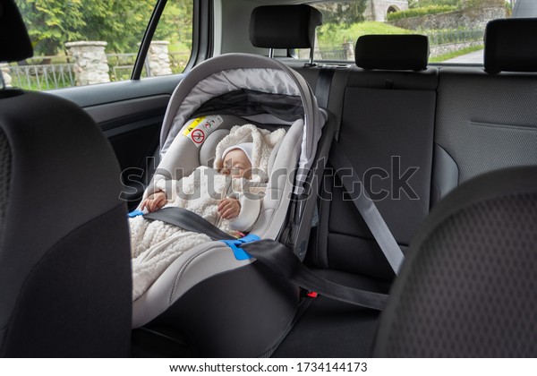Cute three months old baby sleeping in car seat on\
back-seat of the car