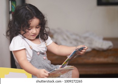 Cute three year old girl enjoy reading a book.