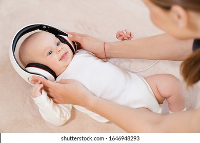 Cute three-month-old baby listening to music in headphones.