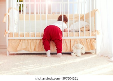 Cute Toddler Baby Climbing Into The Cot In Nursery Room At Home