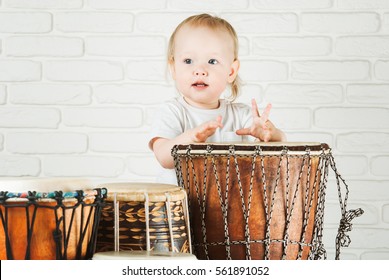 Cute Toddler Baby Playing Ethnic Drums Next To Bricks Wall