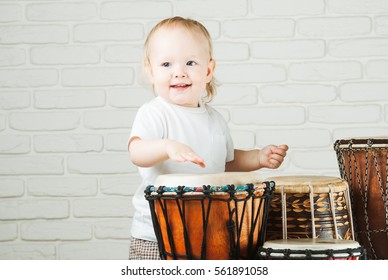 Cute Toddler Baby Playing Ethnic Drums Next To Bricks Wall