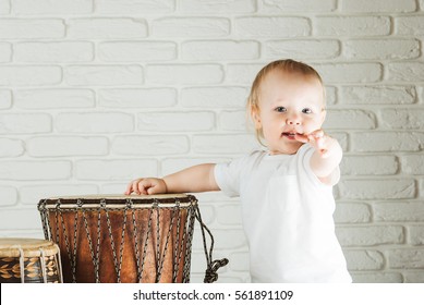 Cute Toddler Baby Playing Ethnic Drums Next To Bricks Wall