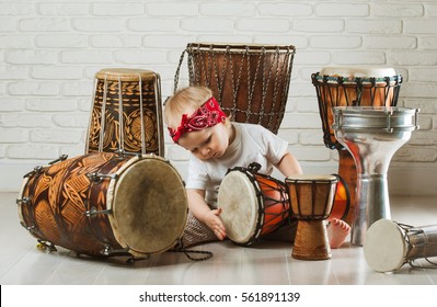 Cute Toddler Baby Playing Ethnic Drums Next To Bricks Wall