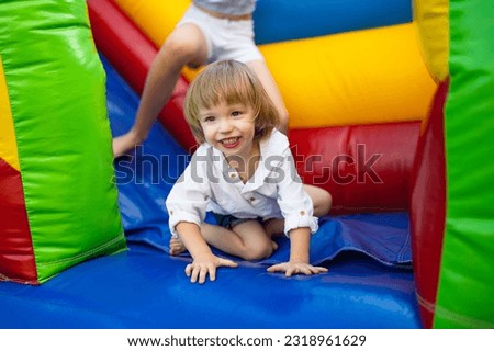 Cute toddler boy jumping on a inflatable bouncer in a backyard on warm and sunny summer day. Sports and exercises for children. Summer outdoor leisure activities.