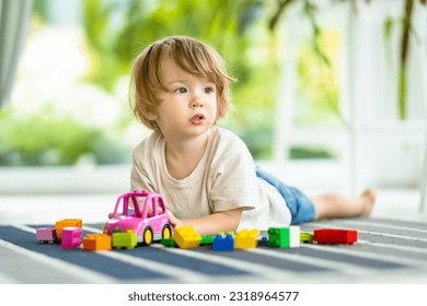 Cute toddler boy playing with blocks construction toy set on the floor at home. Daytime care creative activity. Kids having fun with toys. Educational learning games. Family leisure indoor. - Shutterstock ID 2318964577