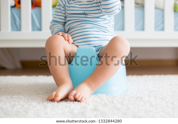 Cute toddler boy, potty training, playing with his\
teddy bear on potty