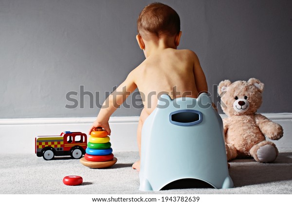 Cute toddler boy, potty training, playing with
pyramid toy on potty