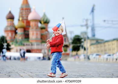 Cute toddler boy running with russian flag with Red Square and Vasilevsky descent on background