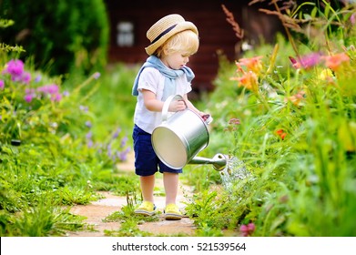 Cute Toddler Boy In Straw Hat Watering Plants In The Garden At Summer Sunny Day

