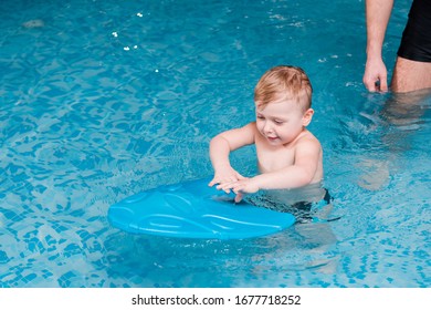 Cute Toddler Boy Swimming With Flutter Board Near Swim Coach