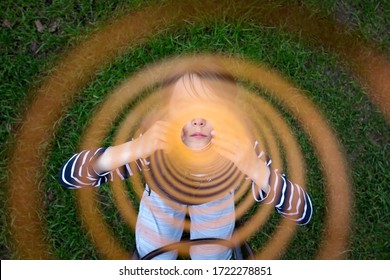 Cute toddler child, blond boy in colorful raincoat, holding slinky toy, dragging it from the camera away, creating interesting effect