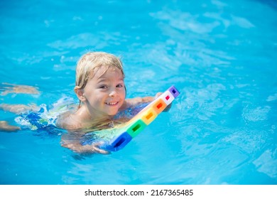 Cute Toddler Child, Boy, Swimming In Pool With Board And Inflatable Ring