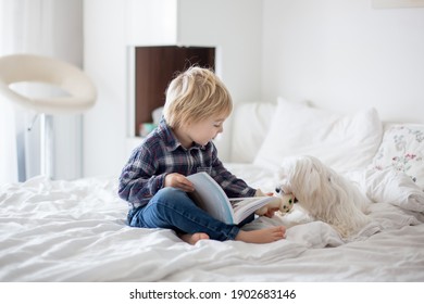 Cute Toddler Child And Puppy Dog, Lying On The Bed, Reading Book Together, Happy Family Time