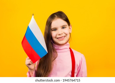 Cute Toddler Girl 6 Y.o. Holding Russian Flag At The Yellow Background.