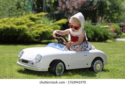 Cute Toddler Girl Driving Big White Toy Car, Having Fun, Riding Away. Resting On Holidays In Park Outdoor
