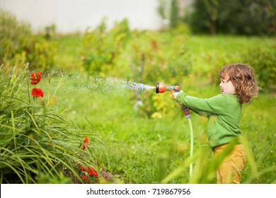 Cute Toddler Girl Having So Much Fun Watering Flowers In The Garden. 