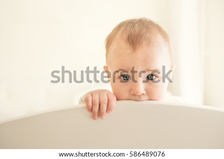 Cute toddler kid biting on a crib, close-up portrait. Baby's teething.