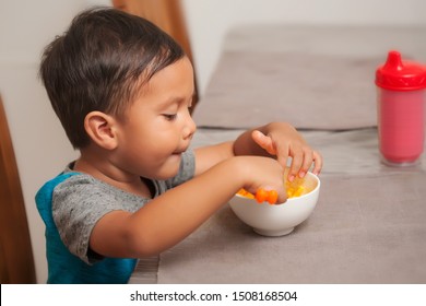 A Cute Toddler Shows Interest In Eating A Mac And Cheese Lunch, And Holds Spoon To Self-feed.