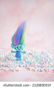 Cute troll with colorful balls decor on blurred pink background close up. Harper Pinsel modern toy hasbro trolls. concept of children's games, fun, toys, friendship