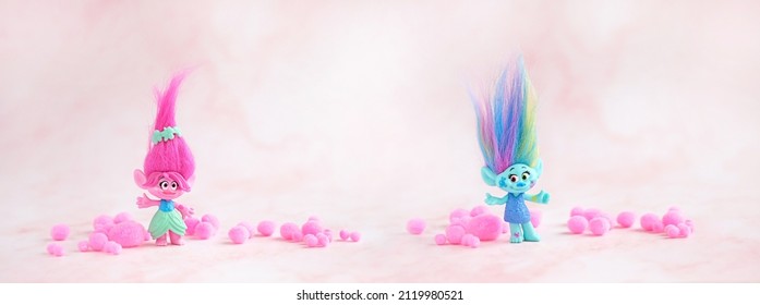 Cute trolls with pink soft balls on blurred pink background close up. Harper Pinsel and Queen Poppy - modern toy hasbro trolls. concept of children's games, fun, toys, friendship. banner