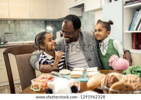 Cute twins. Cute dark-haired twins feeling extremely cheerful while coming to their loving father