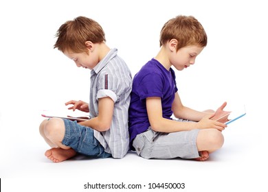Cute twins sitting back to back and exploring the possibilities of modern technologies