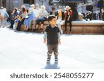 A cute two year old poses in front of the historic fountain in Plaza Real in Barcelona, Spain, at the Gothic Quarter