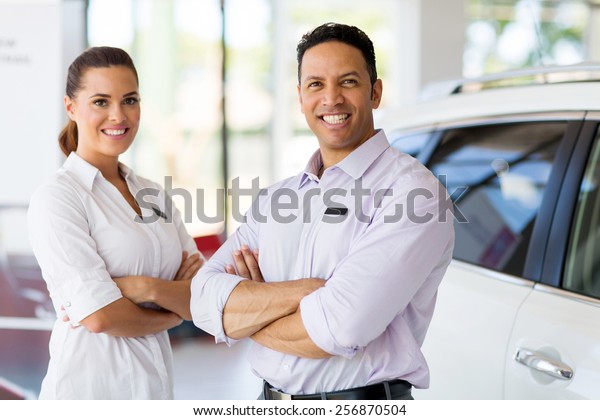 cute vehicle sales staff with arms crossed in\
car showroom
