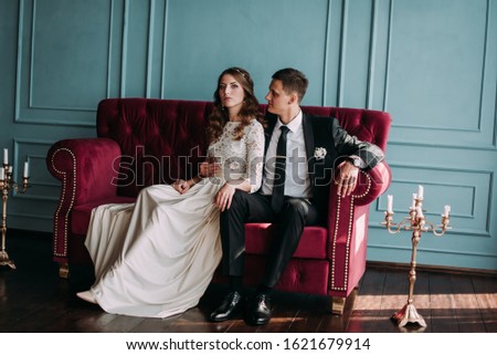cute wedding couple in the interior of a classic studio decorated. hey kiss and hug each other
