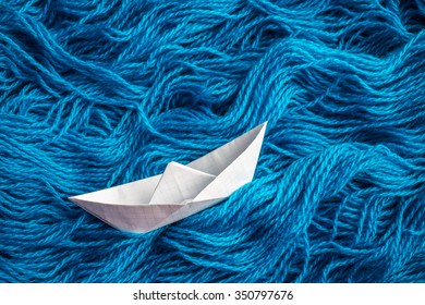 Cute White Of Origami Boat Floats On The Sea Waves Of Woolen Yarn