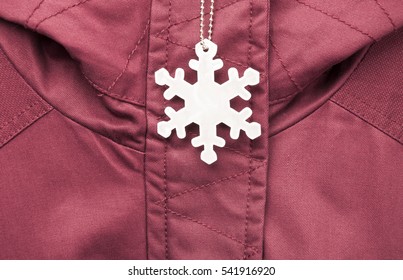 Cute White Safety Reflector In The Form Of Snowflakes On The Winter Jacket. Necessary Equipment To Pedestrians For Walks During Dark Conditions.