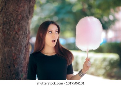 Cute Woman with Cotton Candy Having Fun in the Park. Girl eating an unhealthy sugary treat bringing back childhood memories