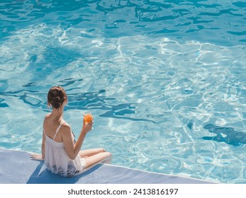 Cute woman with a glass of drink sits near the swimming pool of a cruise ship. Sunny, clear morning. View from above. Closeup, outdoors. Vacation and travel concept - Powered by Shutterstock