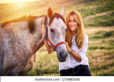 Cute woman hold a horse in nature .