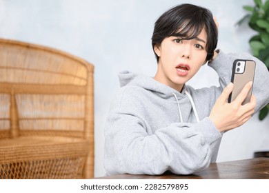 Cute woman holding her phone and holding her head in trouble. looking at camera - Shutterstock ID 2282579895