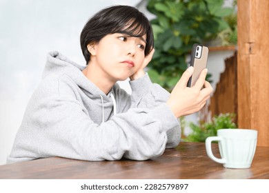 Cute woman holding her phone and holding her head in trouble. - Shutterstock ID 2282579897
