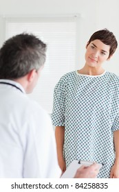 Cute Woman In Hospital Gown Talking To Her Doctor In A Room