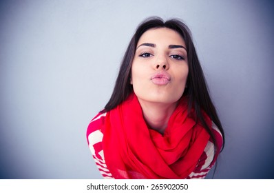 Cute Woman Kissing At Camera Over Gray Background. Wearing In Pink Scarf And Sweater. 