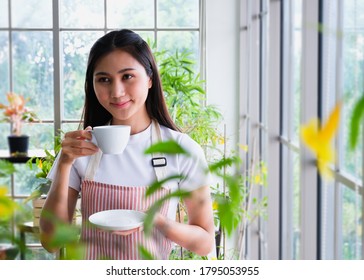 Cute woman are Smile face.Love for coffee. Portrait of Asian girl drinking enjoying her tea on the balcony over outside terrace,Portrait of a satisfied woman thinking looking at side holding a cup. 