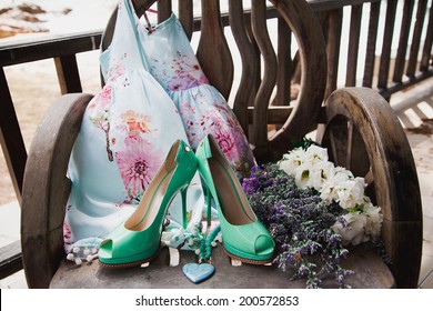 Cute Woman Summer Floral Dress Green, High Heels Pumps , Fashion Blue Heart Necklace And Flowers Laying In Old Wooden Chair. Romantic Retro Composition, Pastel Colors.