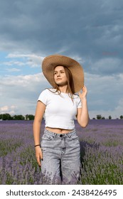 Cute woman in white t-shirt and hat walking in lavender
