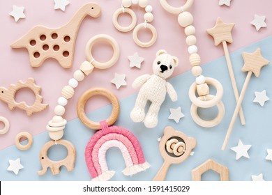 Cute wooden baby toys on pink and light-blue background. Knitted bear, rainbow, dinosaur toy, beads and stars. Eco accessories,  beanbag and teethers for newborn. Flat lay, top view - Shutterstock ID 1591415029