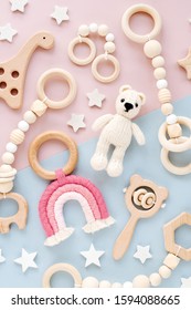Cute wooden baby toys on pink and light-blue background. Knitted bear, rainbow, dinosaur toy, beads and stars. Eco accessories,  beanbag and teethers for newborn. Flat lay, top view - Shutterstock ID 1594088665