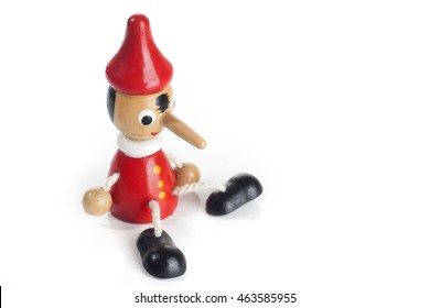 Cute Wooden Doll Of Pinocchio Liar With Big Nose Over White Background.